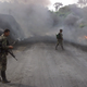 FARC rebels walk by a burning oil pipeline they sabotaged.